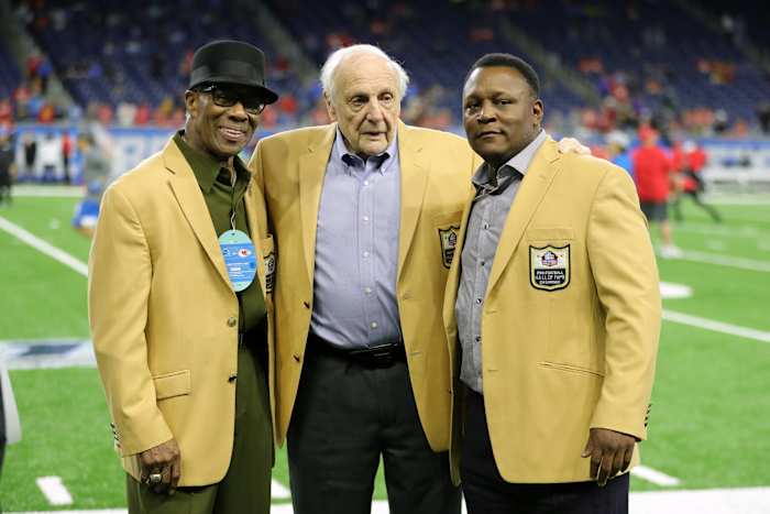 Lions Hall of Famers Lem Barney, Joe Schmidt and Barry Sanders (left to right) stand on the field before a 2019 game at Ford Field.